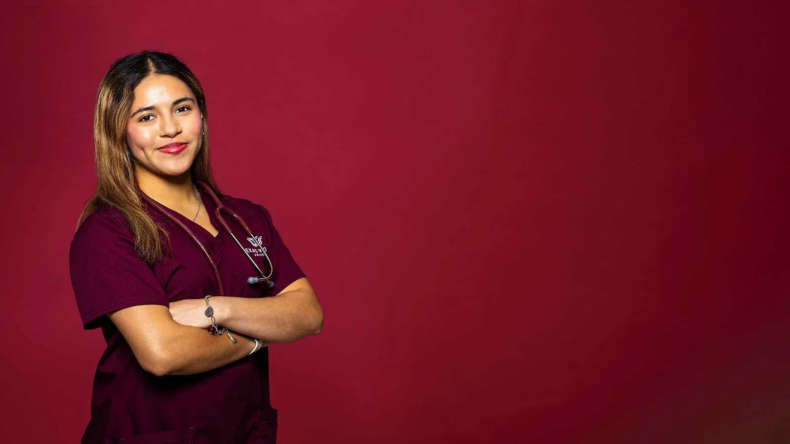A TWU Nursing student wearing maroon scrubs with a stethoscope around her neck