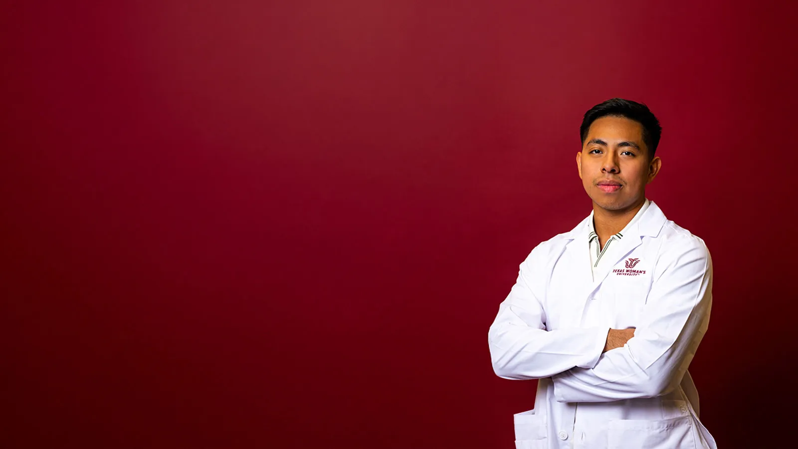 a TWU student wearing a white lab coat with the university logo embroidered on the chest