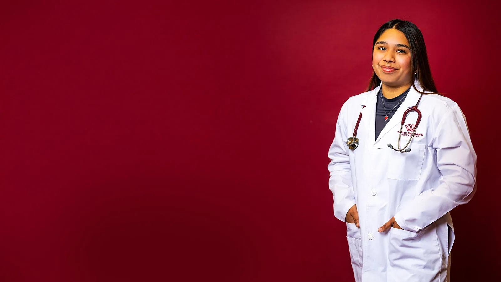 WU student Lauren Lucio stands wearing a lab coat with the university logo embroidered on it