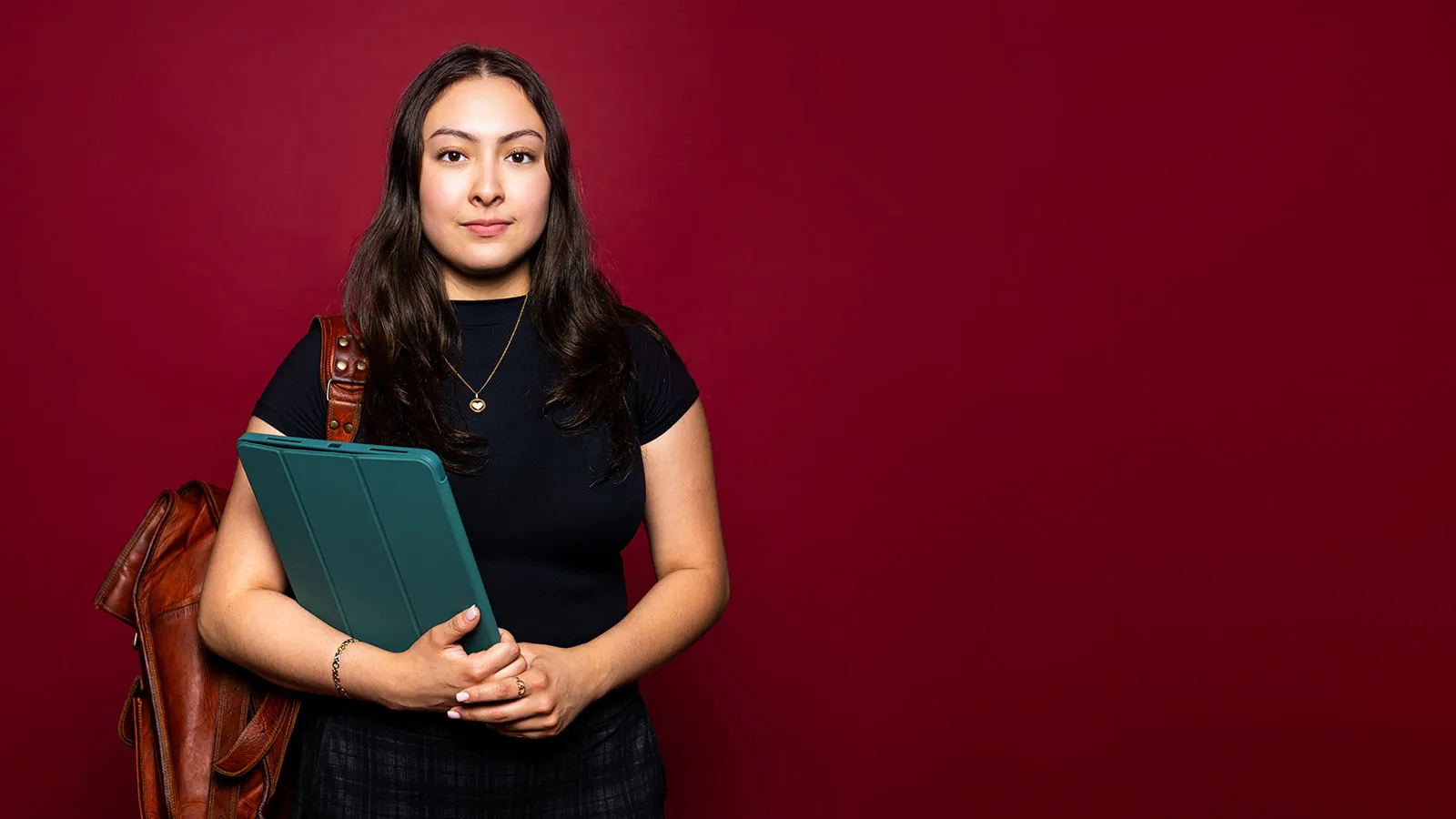 A TWU Student Wearing a Backpack and Holding a Tablet Computer