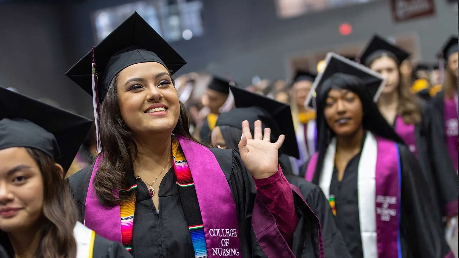 A TWU graduate waving to the crowd