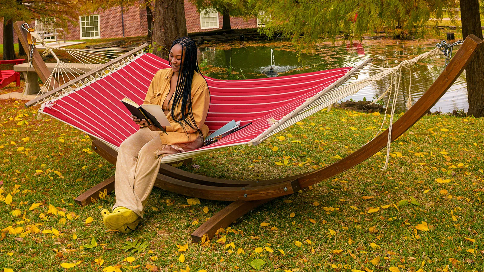 A TWU Student Sitting in a Hammock and Reading a Book