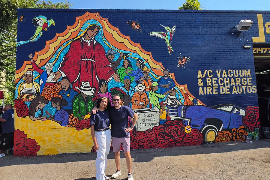 Issy Martinez and Giovanni Valderas stand in front of a mural in Oak Cliff.
