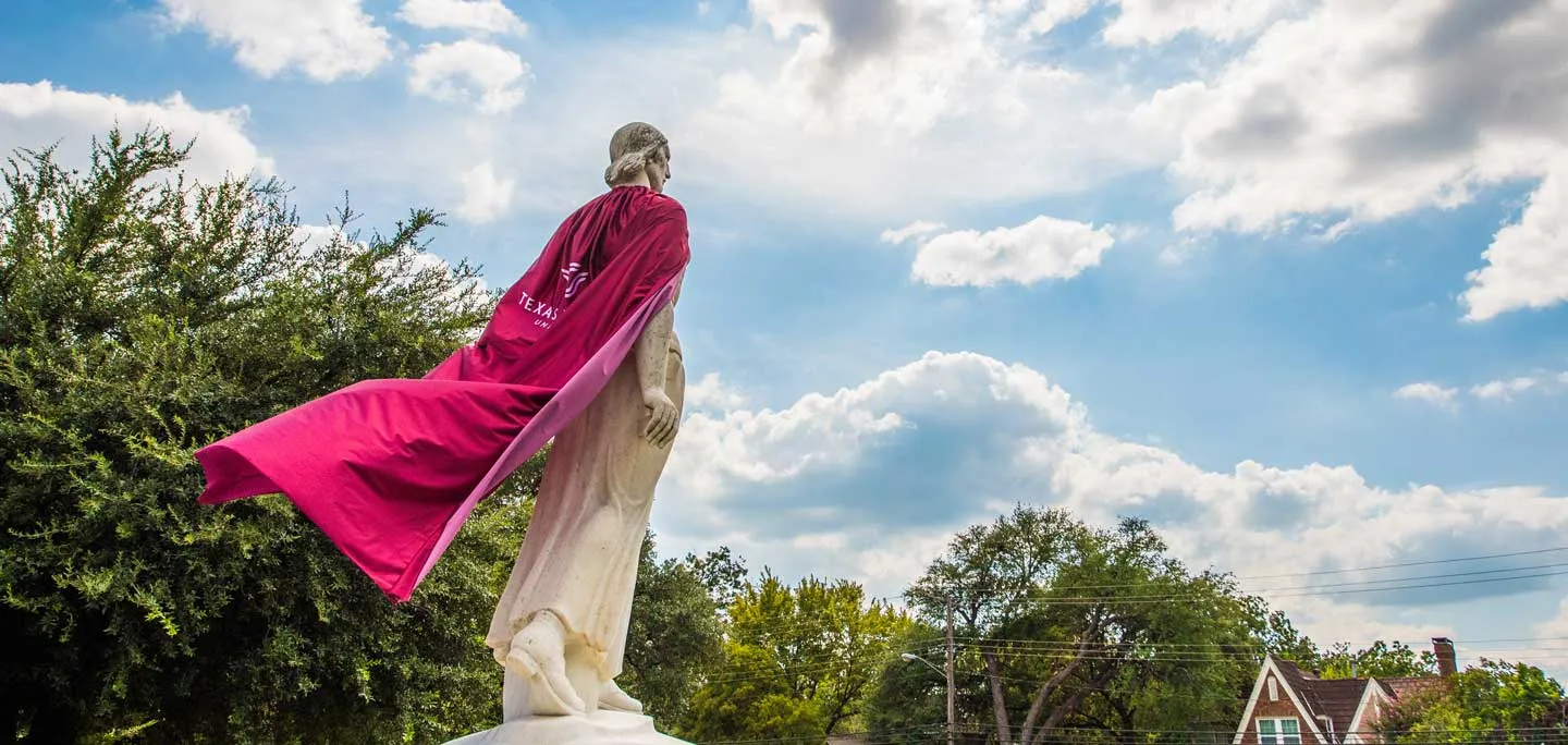 The Pioneer Woman statue with a maroon cape on.