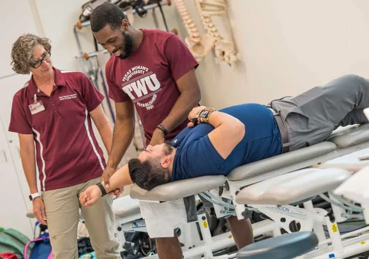 A TWU PT student works with a patient and their professor.