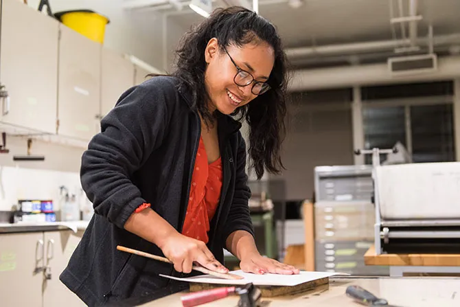 A TWU graduate art student works on a project in an art studio setting.
