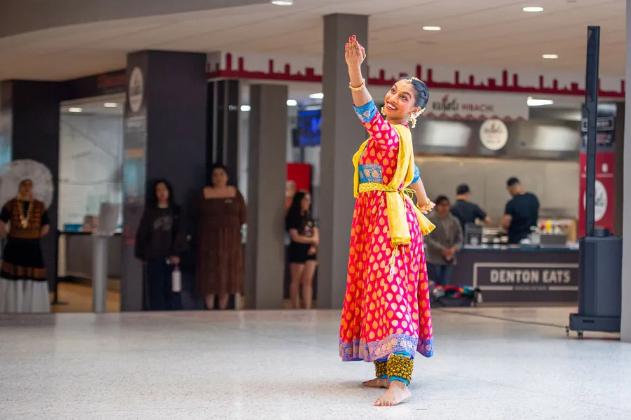 A woman in traditional Indian dress performance a cultural dance in the Student Union.