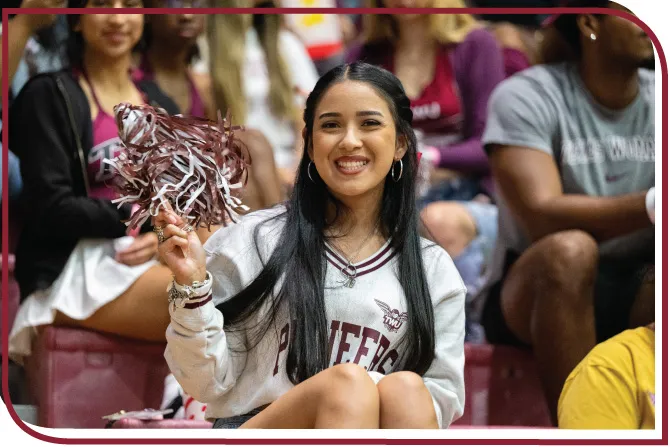 A ��ݮ��ý�������� student waves a pom pom at an athletics event.