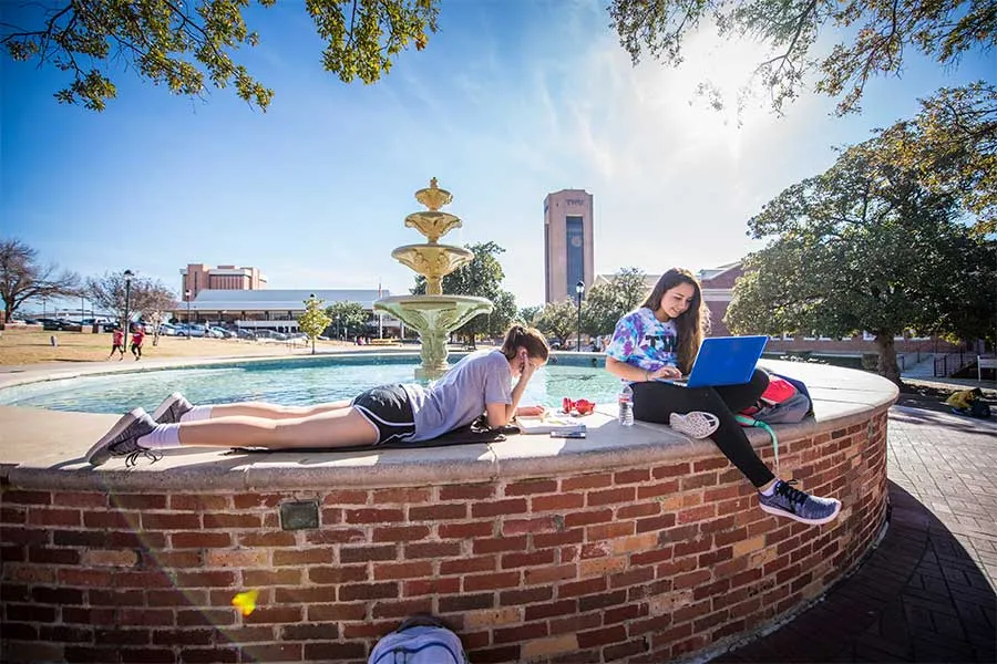 Two TWU students relax by the fountain on the Denton campus.