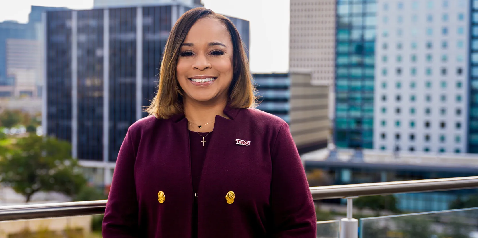 TWU Houston President Monica Williams standing outside the campus, the Houston skyline in the background.