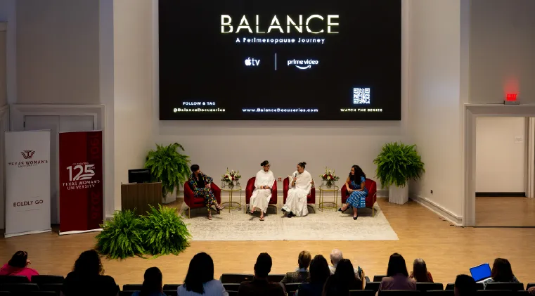 Photo of the BALANCE monk-filmmakers having a panel discussion on stage before an audience with the BALANCE title card on screen in the auditorium on the Denton campus.