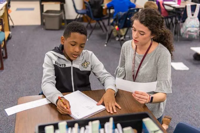 A TWU education student helps a young boy with an assignment