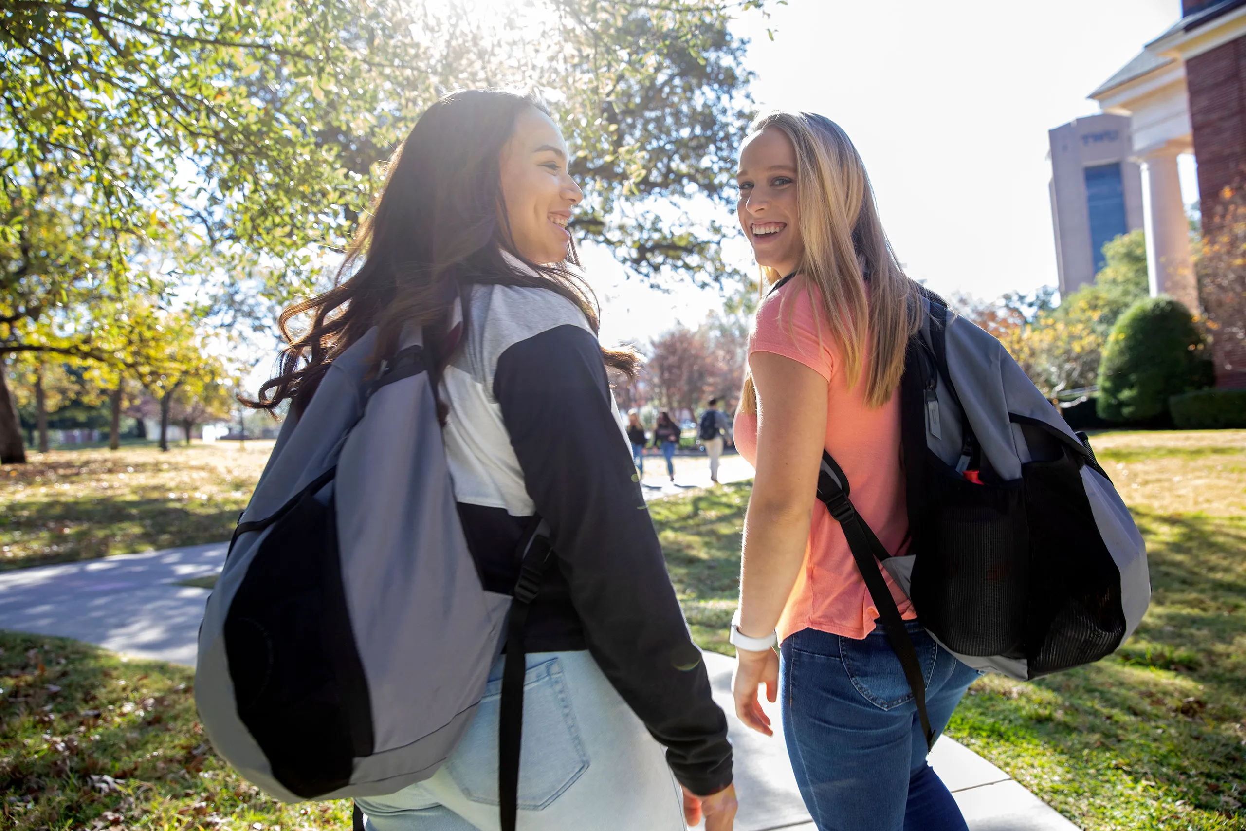 Two TWU students with backpacks walking on campus