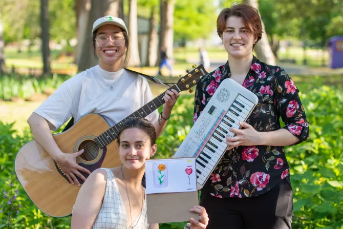 Three TWU students with instruments and art enjoy the campus outdoors.