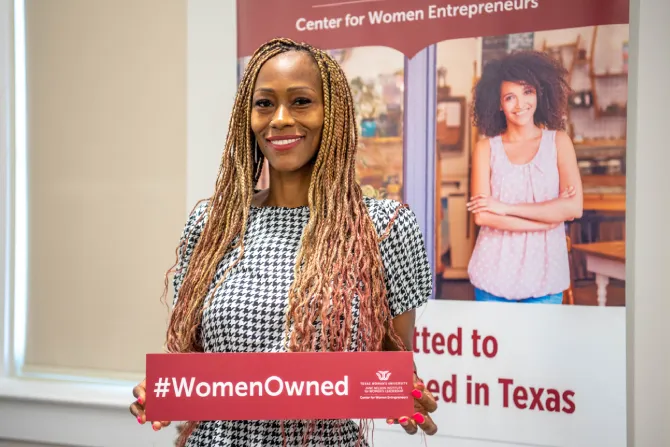 A woman at a JNIWL event holds a TWU sign reading #WomenOwned.