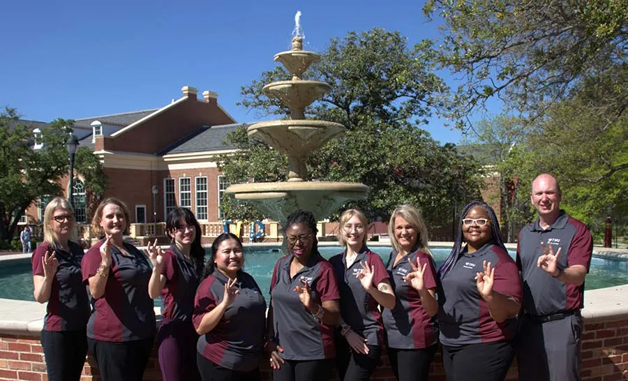 Academic Advising staff in front of the fountain at the Blagg-Huey Library on the TWU Denton campus