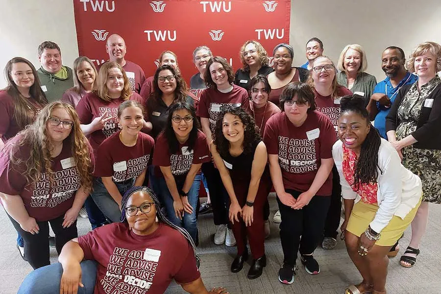 Academic Advising staff in front of a TWU logo backdrop