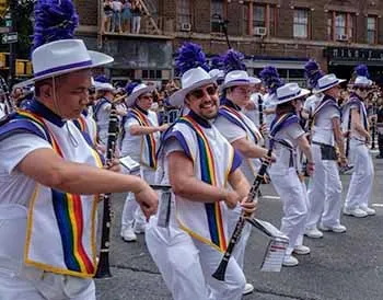 Louis Rendon marching with the band wearing a pride sash.