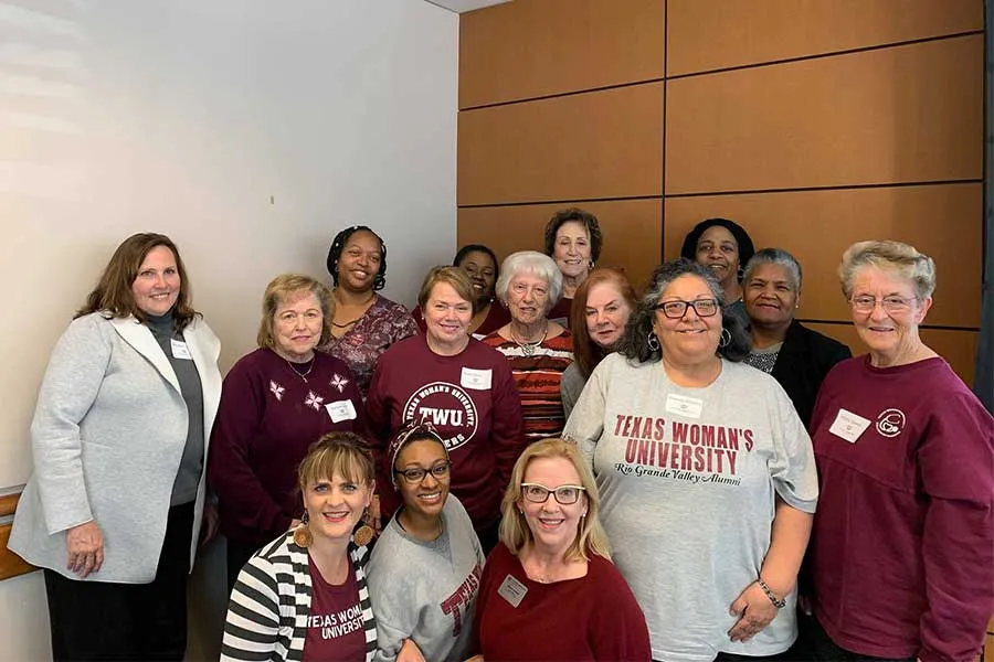A group of TWU alumni smile for a group photo.