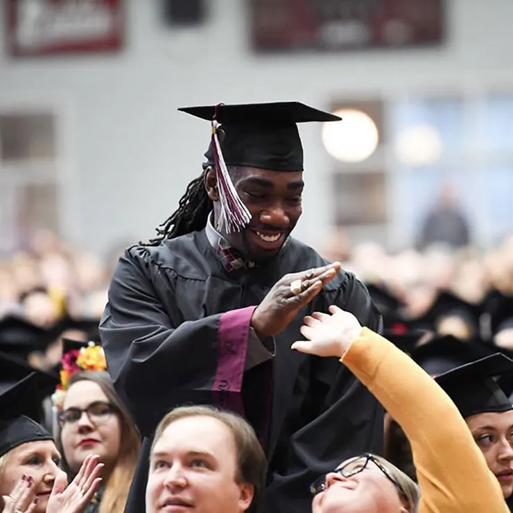 TWU graduate Ryan Matthews high-fives fellow students during his commencement ceremony.