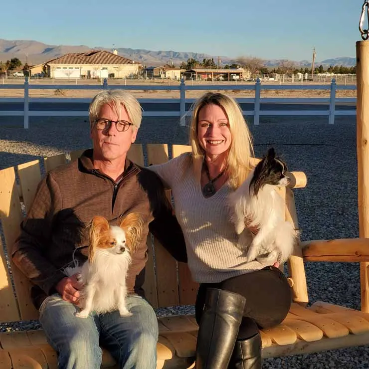 Jody and David Popple sitting on a swing with 2 Papillon breed dogs.