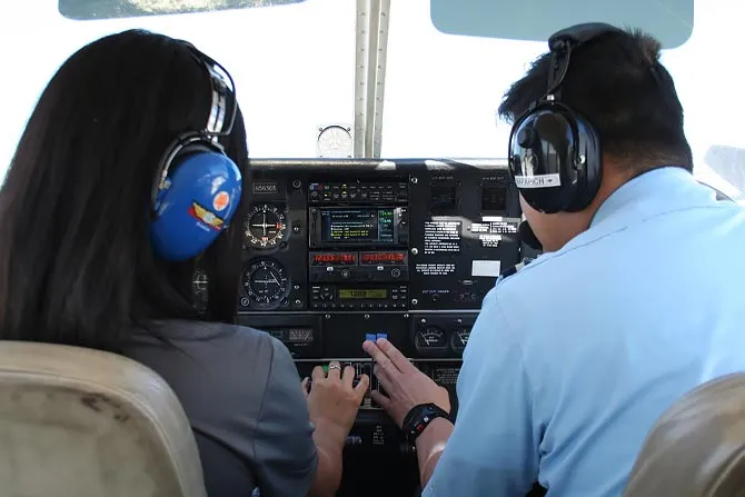 A student and instructor in the cockpit of an airplane