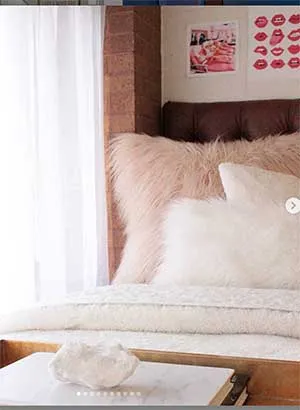 A well made bed in a Stark Hall dorm room with white and pink decor.