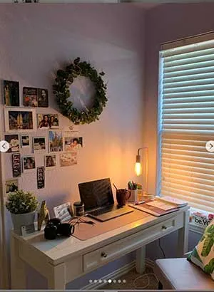A desk area with a laptop on the desk and photos decorated on the wall behind.