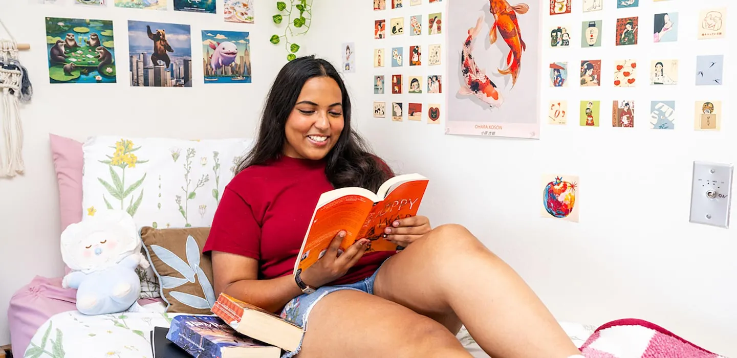 A student reads in bed surrounded by colorful posters and decorations
