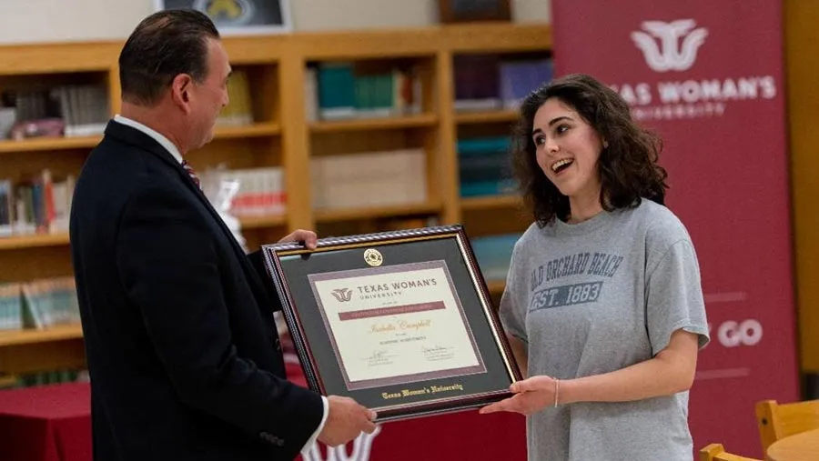 TWU Associate Vice President for Enrollment Management Javier Flores, EdD, presents Isabella Campbell with a certificate commemorating her scholarship award