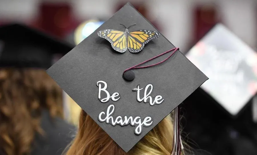 A graduation cap decorated with a butterfly and the words 'be the change'.