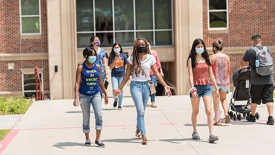 A group of students in protective face masks walking out of the Ann Stewart Science Complex