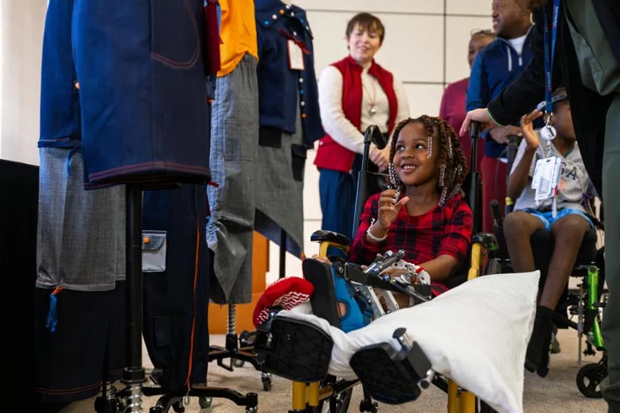 a young girl in a wheelchair at Scottish Rite Hospital receives clothing designed by TWU Fashion & Merchandising students