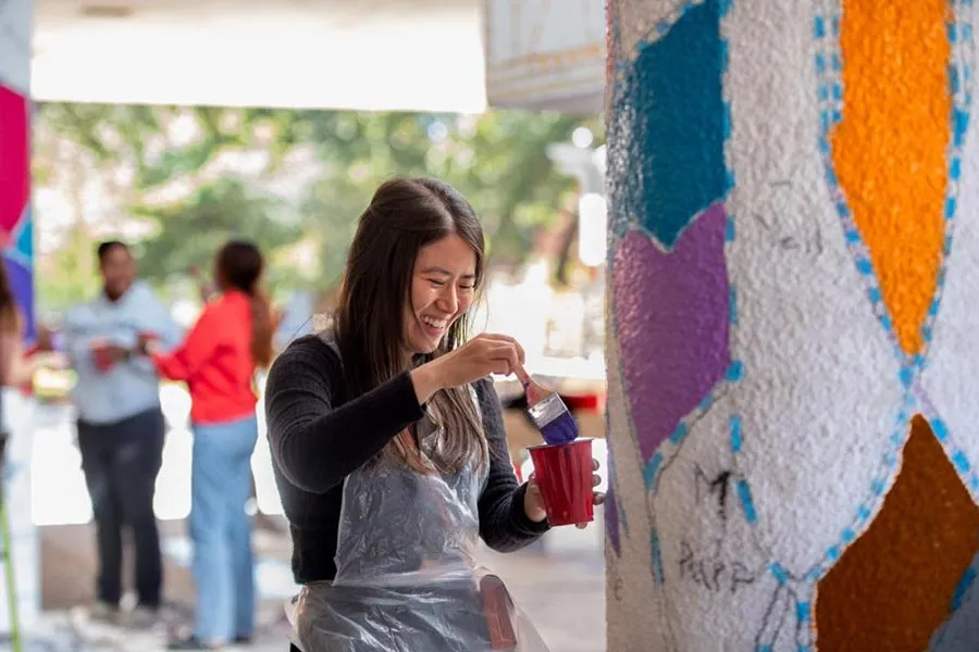 TWU Visual Arts student works on the mural at the ACT building