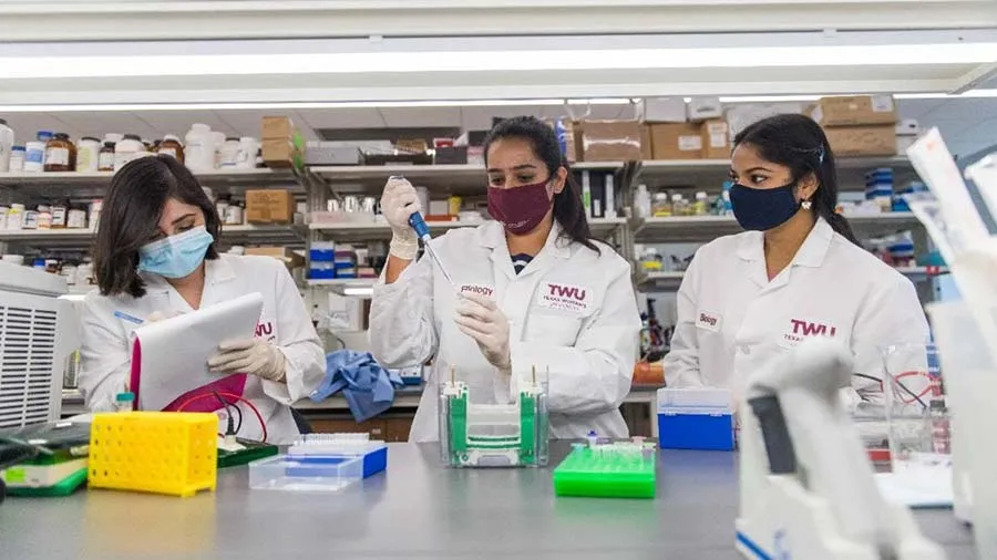 TWU students in lab coats working