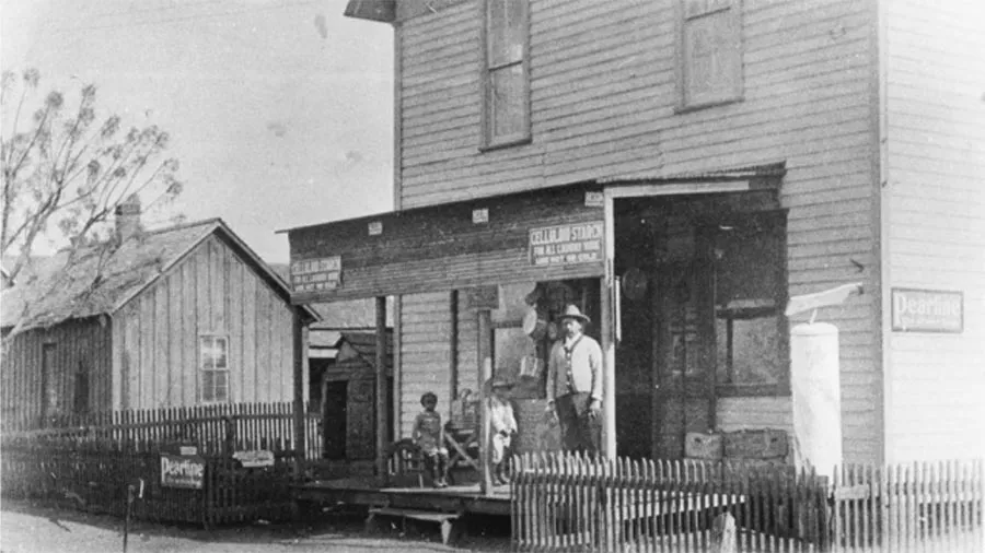 A man and two children stand on the porch of a business in Quakertown in Denton, TX