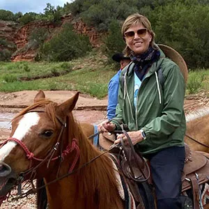 Chancellor Carine Feyten sits astride a horse, smiling