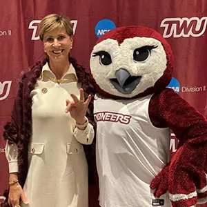 Chancellor Carine M. Feyten with TWU mascot Oakley, making the TWU hand sign