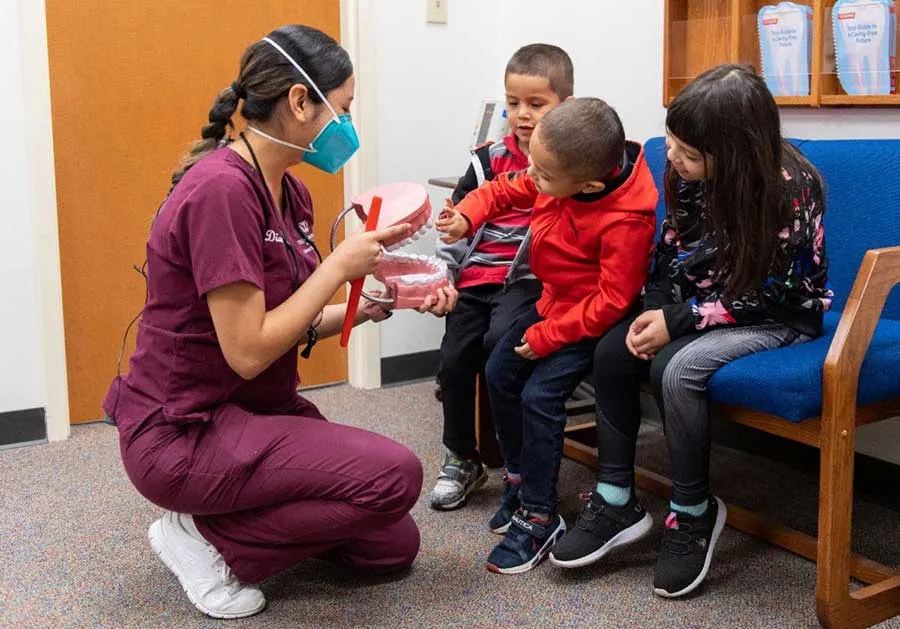A TWU Dental Hygiene student shows children a giant model of teeth and how to brush them