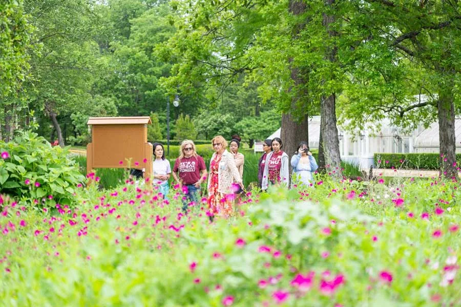 A group of women walk along the paths of the TWU Butterfly Garden on the Denton campus