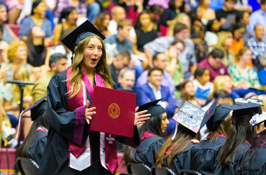 A TWU graduate walks across the stage during Spring 2024 commencement.