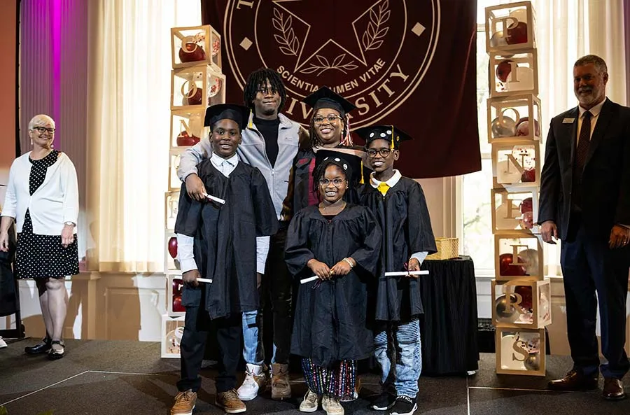 A family all wearing graduation caps and gowns take a photo together during the TWU Family Graduation Celebration