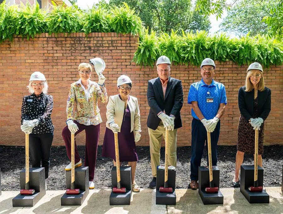 Chancellor Feyten, Dean Yelkur, and others pose with sledgehammers and hard hats in front of the Graduate Research Building on the TWU Denton campus
