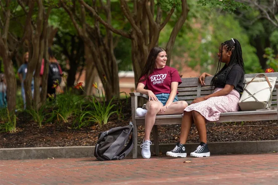 TWU students sitting together on a bench at the Denton campus
