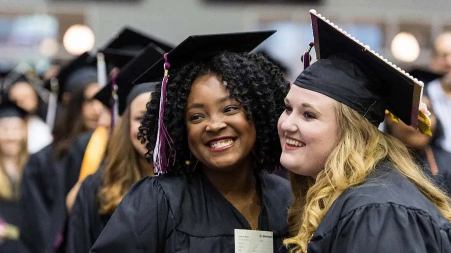 Two graduates pose for a photo during commencement