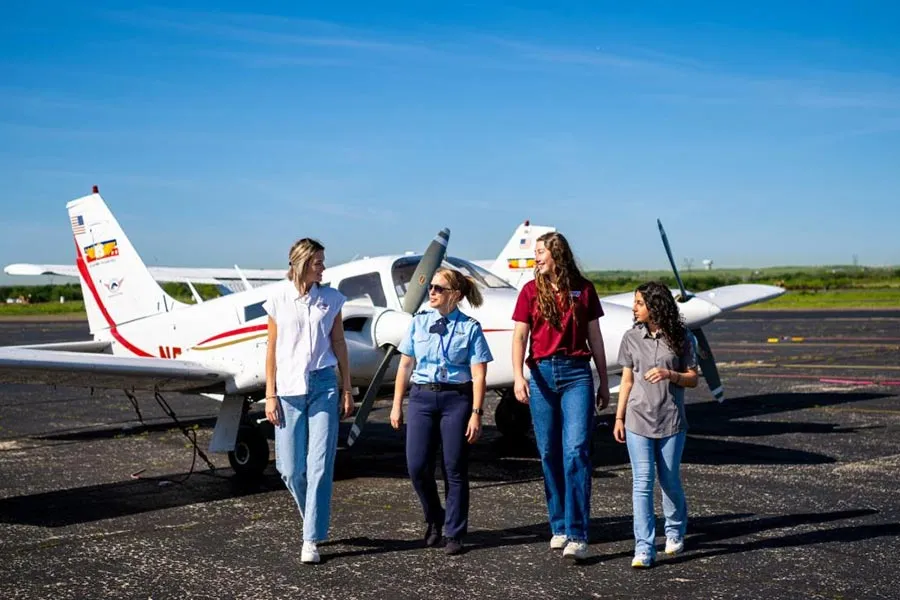 Students from the first cohort of the TWU Doswell School of Aeronautical Sciences on an airport tarmac with a flight instructor