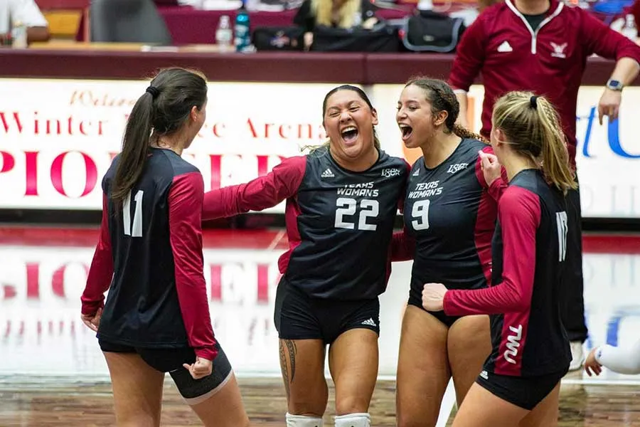 Members of the TWU volleyball team celebrate a win on the court