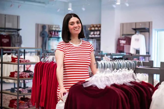 A TWU student shops and browses maroon t-shirts in the bookstore.