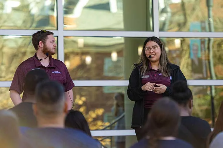 Two TWU Pioneer Ambassadors speak in front of a group of prospective students and parents during a campus tour.