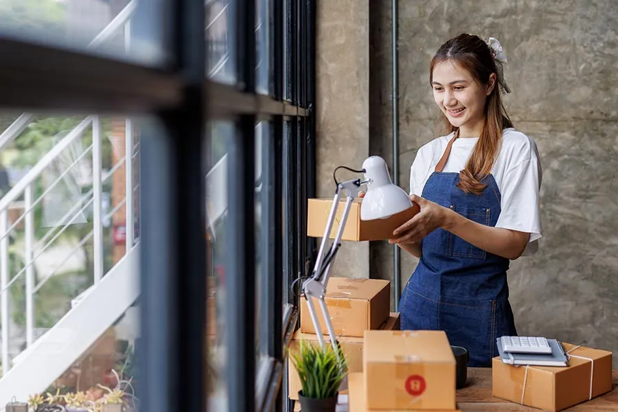A young woman unpacks boxes as she furnishes her new business office